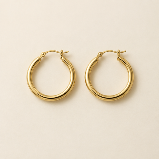 Pair of classic gold hoop earrings on ivory background